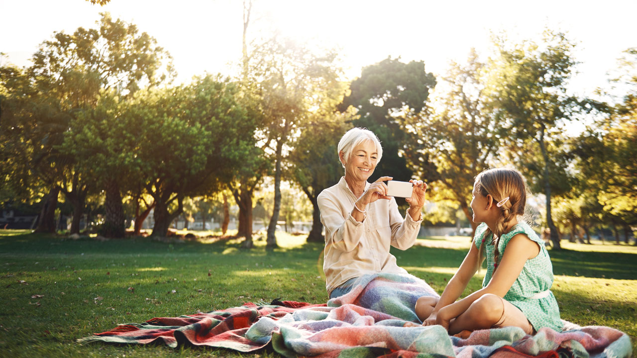 Older woman taking picture of her granddaughter